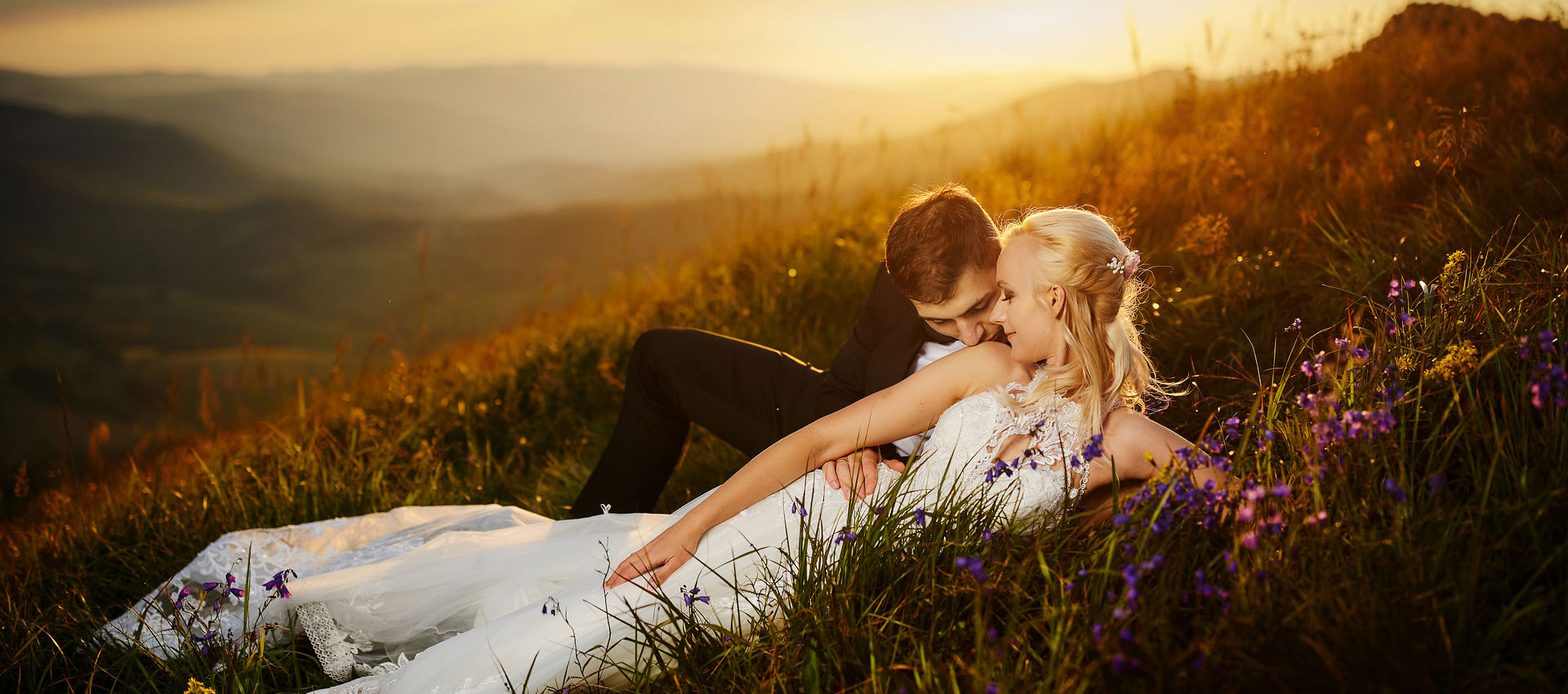 Fotograf ślubny - pan młody i panna młoda o zachodzie słońca na polanie w górach